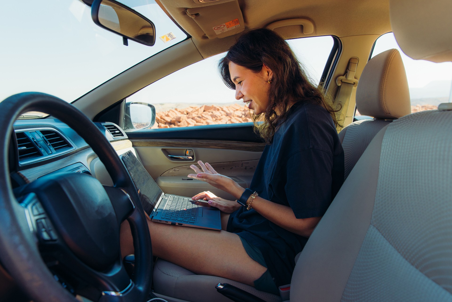 Happy Woman Freelance Working by Laptop in Car During Road Trip