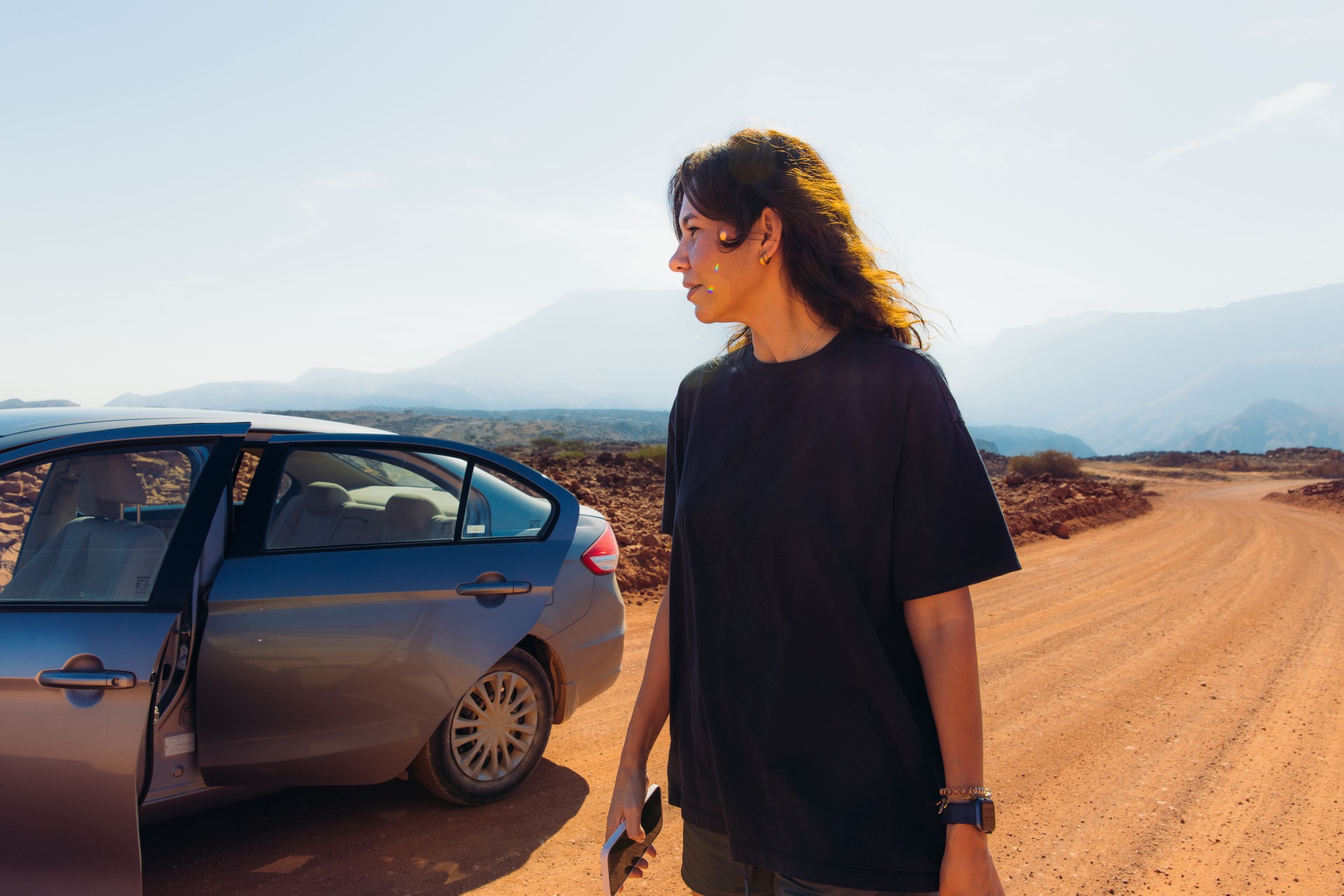Woman Contemplating Mountains During Road Trip by Rental Car